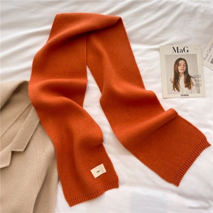 Close-up of bright orange knitted scarf texture with ribbed edge and minimalist label