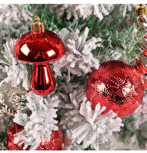 Close-up of red mushroom ornament and swirl pattern bauble on snowy Christmas tree branches