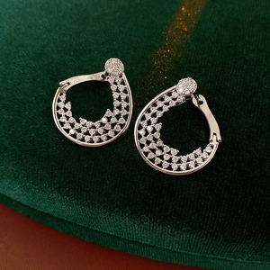 Detail of silver paved zircon flower hoop earrings on dark green velvet background