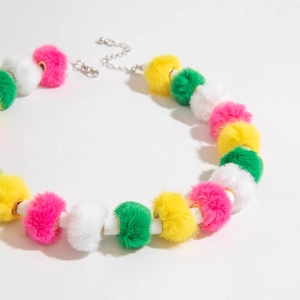Détail de pompons en peluche colorés et de perles blanches sur un collier de Noël festif