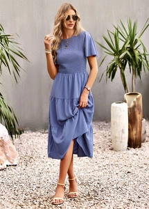 Detailed close-up of the smocked waist and tiered skirt layers on a blue summer dress