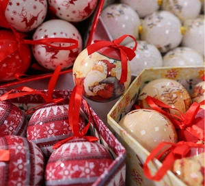 Detailed view of Christmas ornaments with festive patterns and red ribbons in a gift box