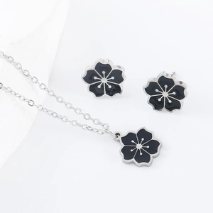 Detailed view of black flower necklace and stud earrings set with silver-tone metal edges
