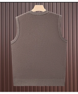 Close-up of brown knit vest sweater texture against a rustic dark wood background