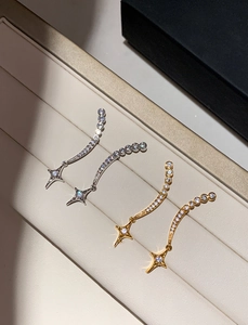 Macro detail of silver and gold star pendant earrings with pavé set cubic zirconia