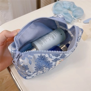 Close-up of blue floral embroidery cosmetic bag with smooth zipper and ample storage