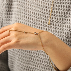 Dettaglio di un bracciale da dito placcato oro con tre pietre di zircone su una mano