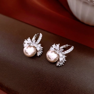 Macro detail of 18k gold plated pearl earrings with sparkling zircon butterfly accents