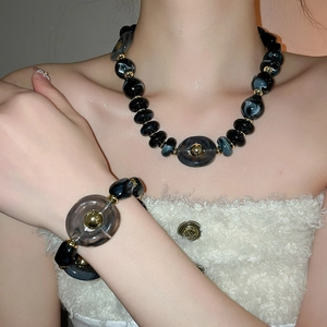 Detail of acrylic irregular black and grey beaded necklace set worn on model