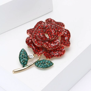 Exquisite rose brooch with red rhinestones, green leaves and gold stem on white background