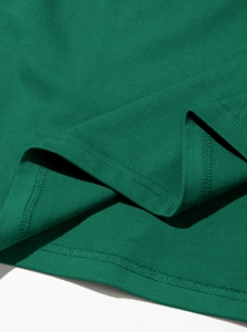 Detailed macro view of the double-stitched hem on a dark green premium cotton T-shirt