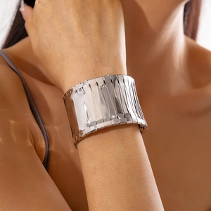 Detailed macro view of glossy silver wide metal cuff bracelet with geometric pleated texture