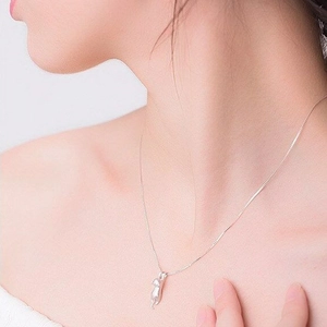 Close-up of minimalist silver kitten pendant necklace worn on a woman's collarbone