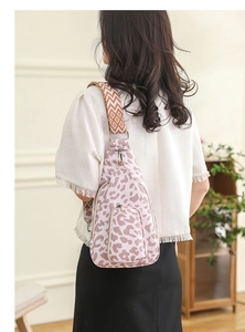 Detail of leopard print crossbody bag with wide geometric strap worn by model