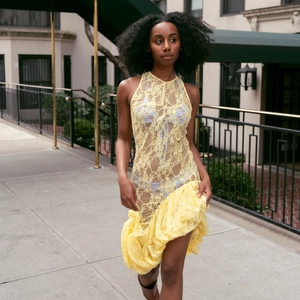 Détail de la robe jaune sans manches en dentelle transparente avec un ourlet asymétrique