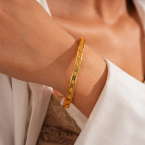 Détail d'un bracelet jonc plaqué or 24 carats avec motifs d'étoiles en zircon au poignet
