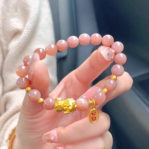 Close-up of pink sunstone beaded bracelet featuring golden PiXiu and Lucky charm pendant