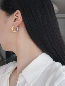 Detailed close-up of a model wearing a two-tone gold and silver chunky hoop earring