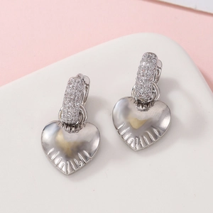 Detailed macro view of heart earrings with sparkling cubic zirconia on a geometric stand