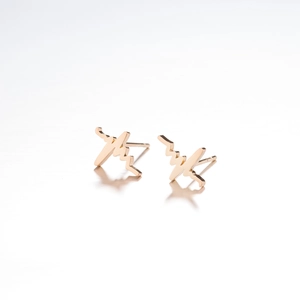 Macro shot of minimalist gold stainless steel heartbeat studs with reflective mirror finish
