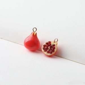 Detailed view of red pomegranate resin charms with gold loops for DIY jewelry making