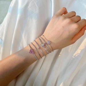 Detail of S925 silver tennis bracelets with pink heart zircon on white silk background
