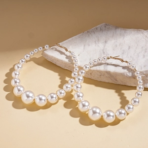 Elegant gold hoop earrings with white faux pearls on stone background for women