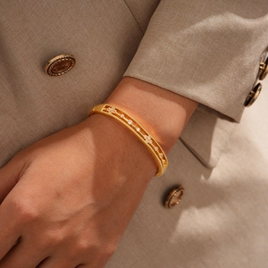Close-up of 18k gold-plated cuff bracelet with zircon flowers on a beige suit