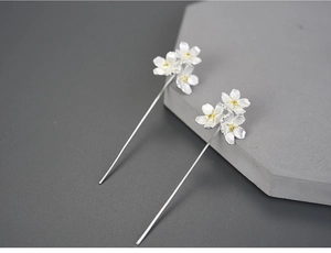 Detail view of handmade S925 silver forget-me-not flower earrings on grey stone
