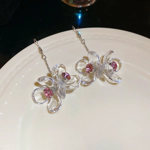Macro view of crystal acrylic flower earrings with pink rhinestones and silver chain tassels
