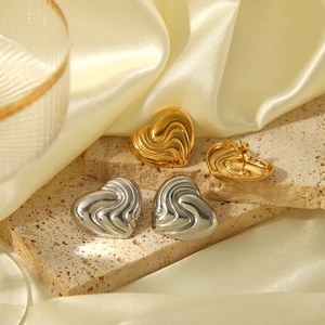 Dettaglio di orecchini a cuore oro e argento con texture a onde fluide 3D lucide