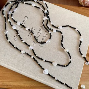 Vintage beaded necklace with black faceted beads, white pearls, and stars on a book