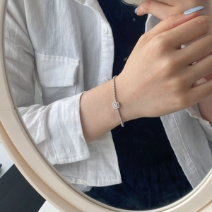 Close-up of a silver tennis bracelet with a square zircon pendant worn on the wrist