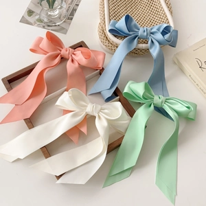 Satin oversized bow hair clips in pastel colors displayed on an elegant wooden tray