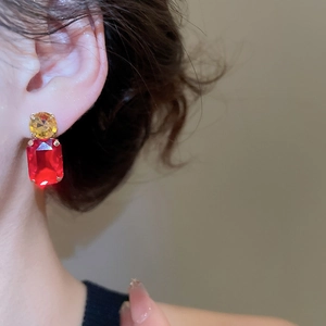 Detailed close-up of double-layered earrings with yellow round and red square crystals