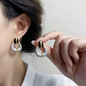 Macro detail of retro gold-plated enamel earrings with black oval stone and metal horseshoe charm