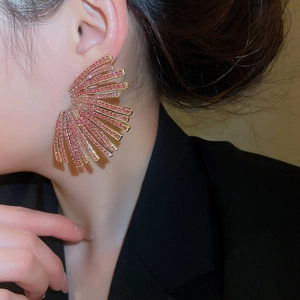 Macro view of gold fan earrings with pink rhinestones on a model for formal events