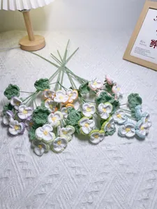 Handcrafted crochet lily of the valley flowers with colorful petals on white cloth