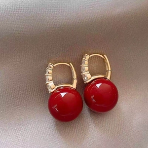 Gold plated hoop earrings with red pearls and sparkling zircon on champagne silk fabric