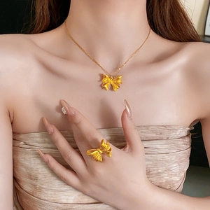Detailed view of elegant gold butterfly necklace and ring set on female model