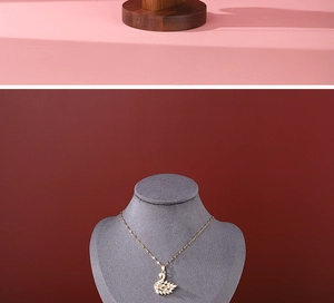Detailed view of a swan pendant necklace displayed on a walnut bust stand