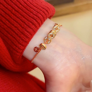 Détail d'un bracelet de pièces porte-bonheur plaqué or avec corde tressée rouge