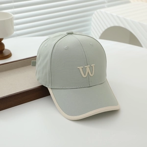 Detail of mint green baseball cap with beige brim edging and embroidered W letter