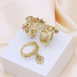 Detail of gold copper rings with dangling cross, heart, and turtle charms in zirconia