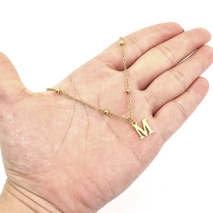 Minimalist gold letter M pendant necklace with thin beaded chain for modern women