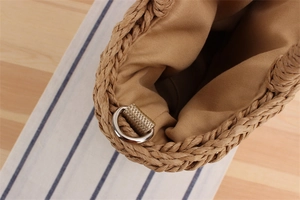 Detail view of woven paper straw bag with beige fabric lining and silver D-ring buckle