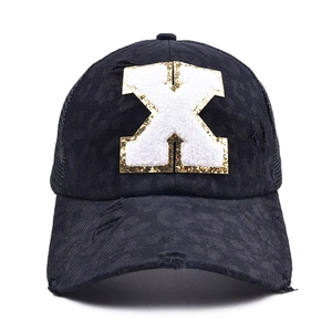 Detail of black baseball cap featuring leopard print fabric and chenille letter X embroidery
