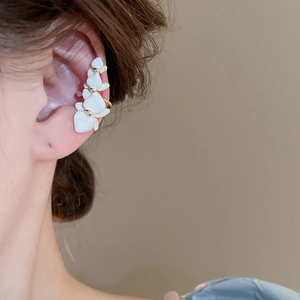 Close-up of gold-plated white orchid ear cuff clip with cream petals on female ear