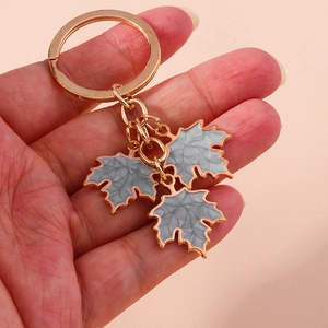 Detail showing hand holding rose gold ginkgo leaf keychain with marble texture