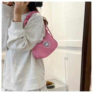 Detailed view of pink fabric shoulder bag featuring ruffled straps and heart patch